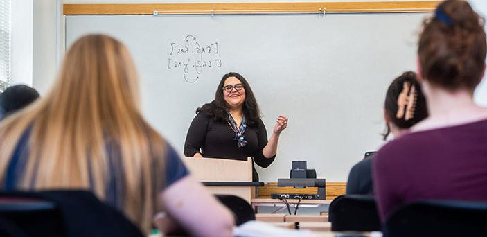 Professor Fernanda Ferreira smiling while teaching Spanish Phonetics in front of a white board while students look on